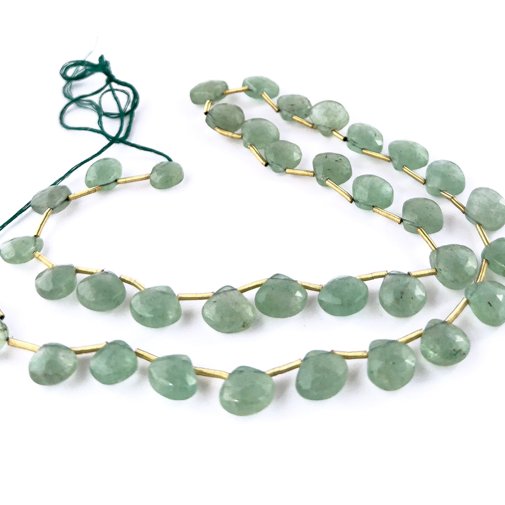 Close‑up of Green Strawberry Quartz faceted briolette beads highlighting their reflective surfaces and sparkling green-tone inclusions.