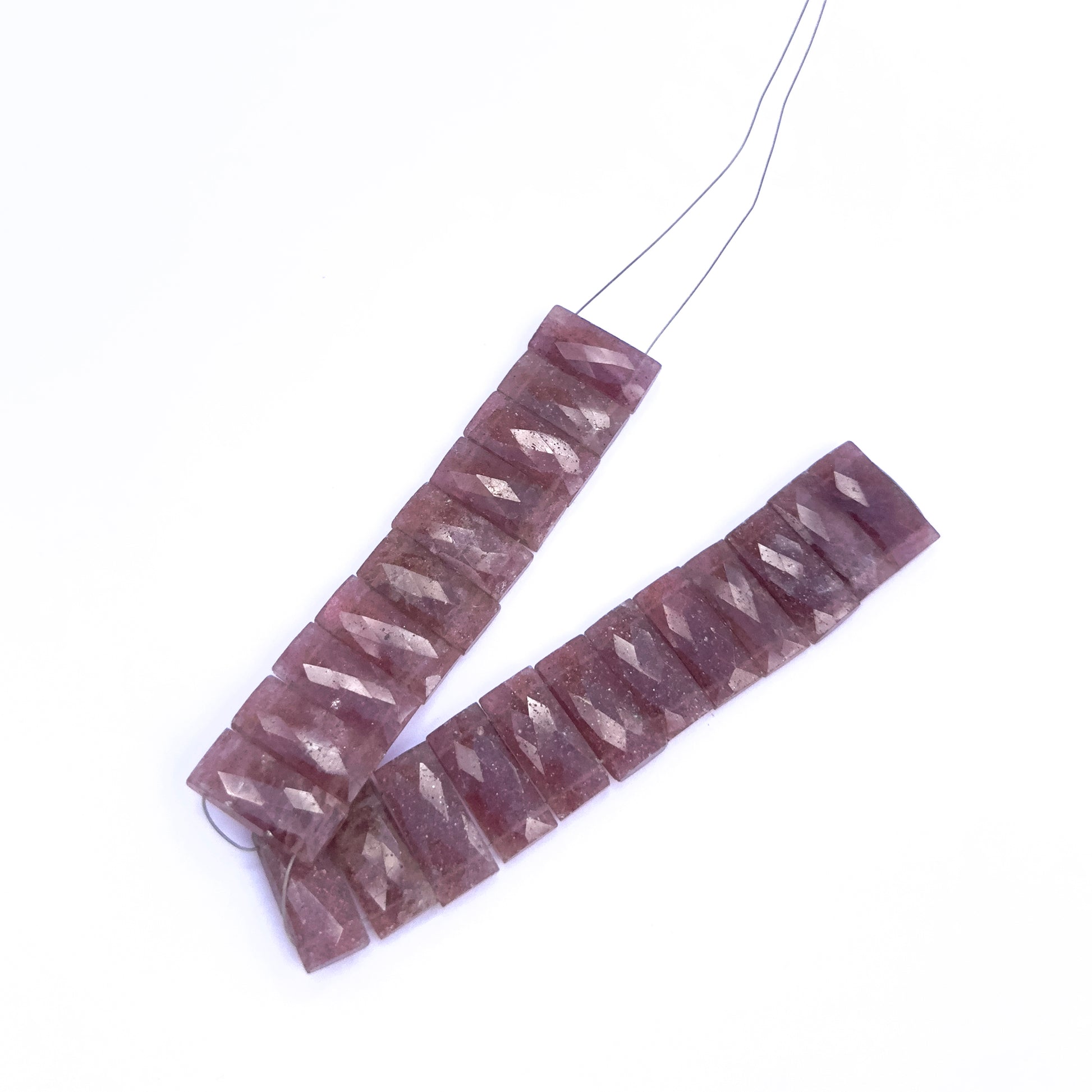 Strawberry Quartz gemstone beads laid flat to highlight their faceted surface and rectangular shape.