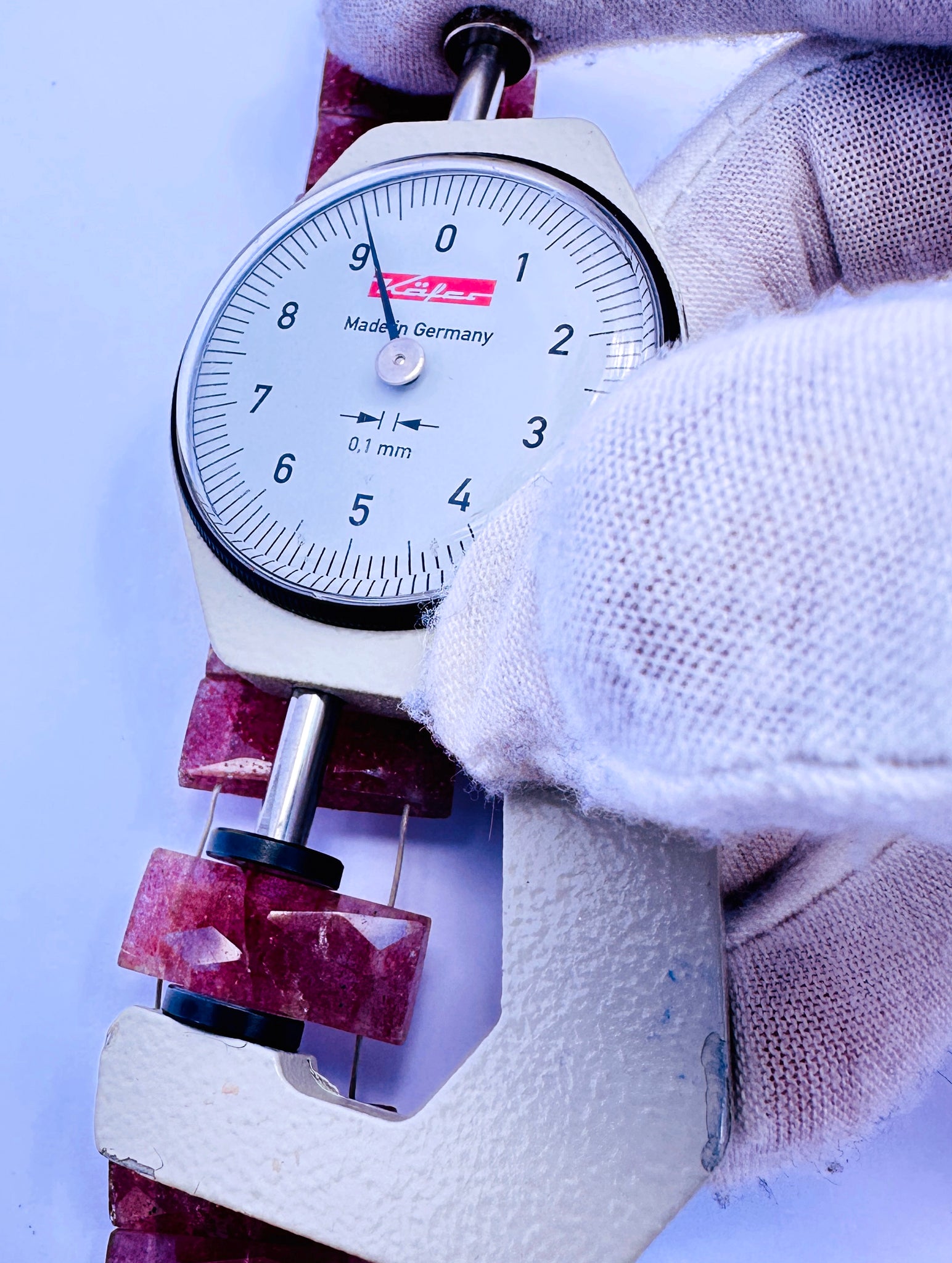 A dial gauge measures the Strawberry Quartz faceted rectangle 21×9.2–9.5mm gemstone.