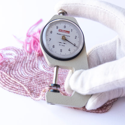 A dial gauge measures the Strawberry Quartz faceted rondelle 3.2mm gemstone.