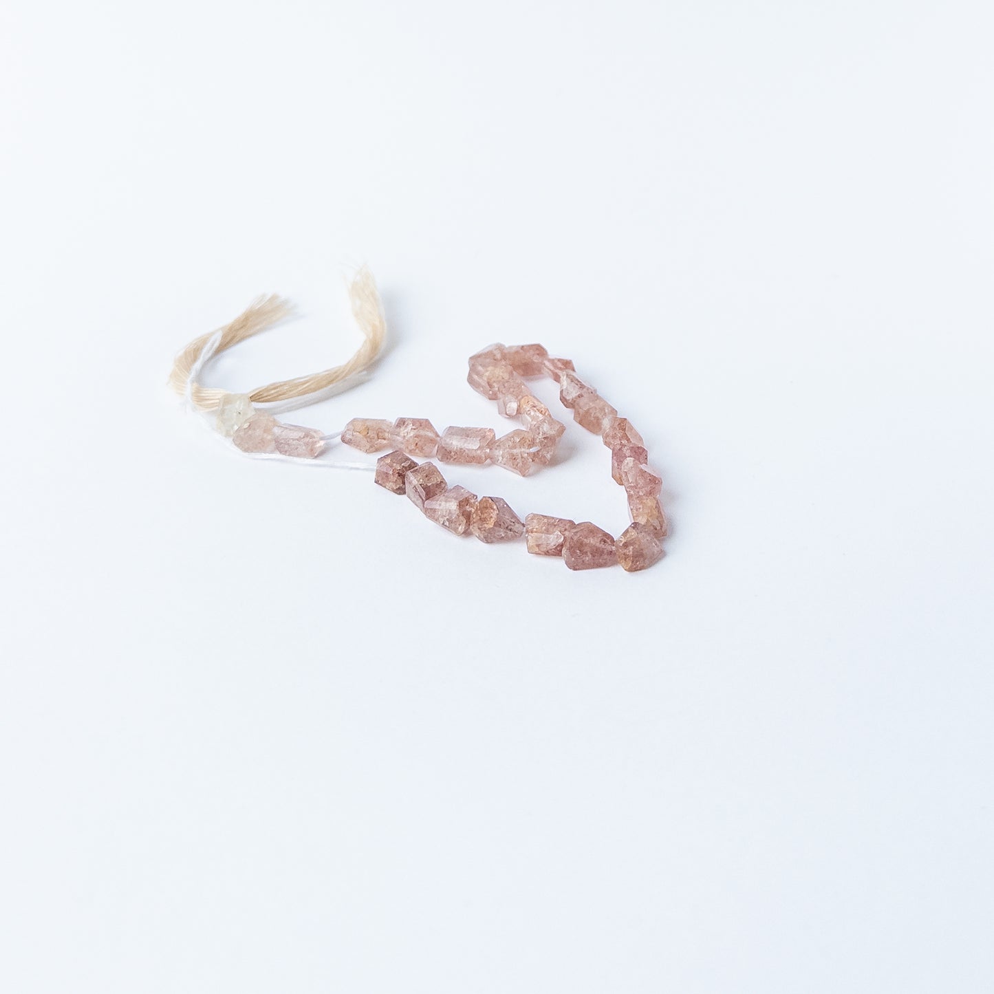 Genuine Strawberry Quartz gemstone beads arranged on a 22cm strand, showcasing clarity and shimmering texture.