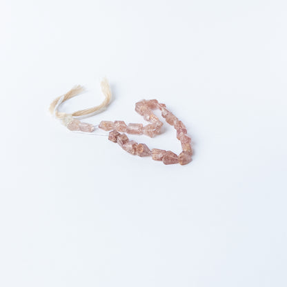 Genuine Strawberry Quartz gemstone beads arranged on a 22cm strand, showcasing clarity and shimmering texture.