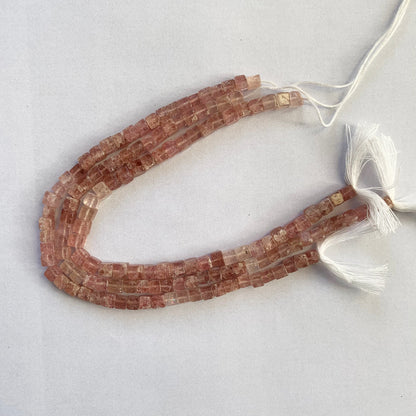 Gemstone strand featuring Strawberry Quartz cubes with delicate pink hues and smooth surfaces.