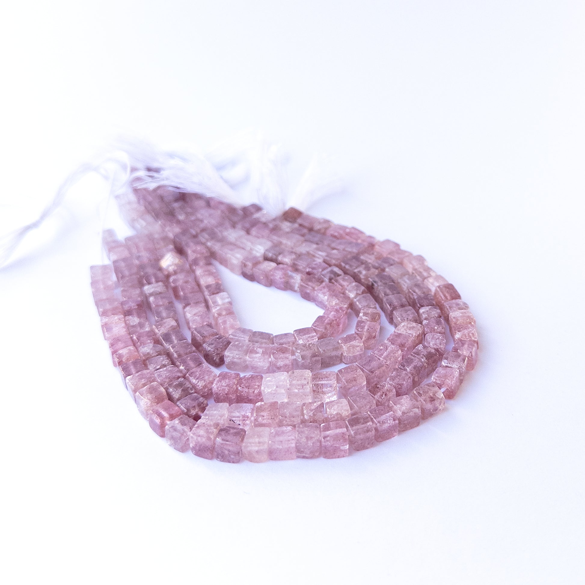 Handmade jewellery components featuring natural strawberry quartz smooth cube beads in a neatly aligned strand.