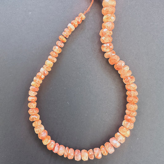 Close-up of Sunstone faceted rondelle beads with golden-orange tones and sparkling facets.