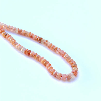 Sunstone faceted rondelle natural gemstone beads with warm peach sparkle arranged on a 20cm strand for handmade jewellery components.