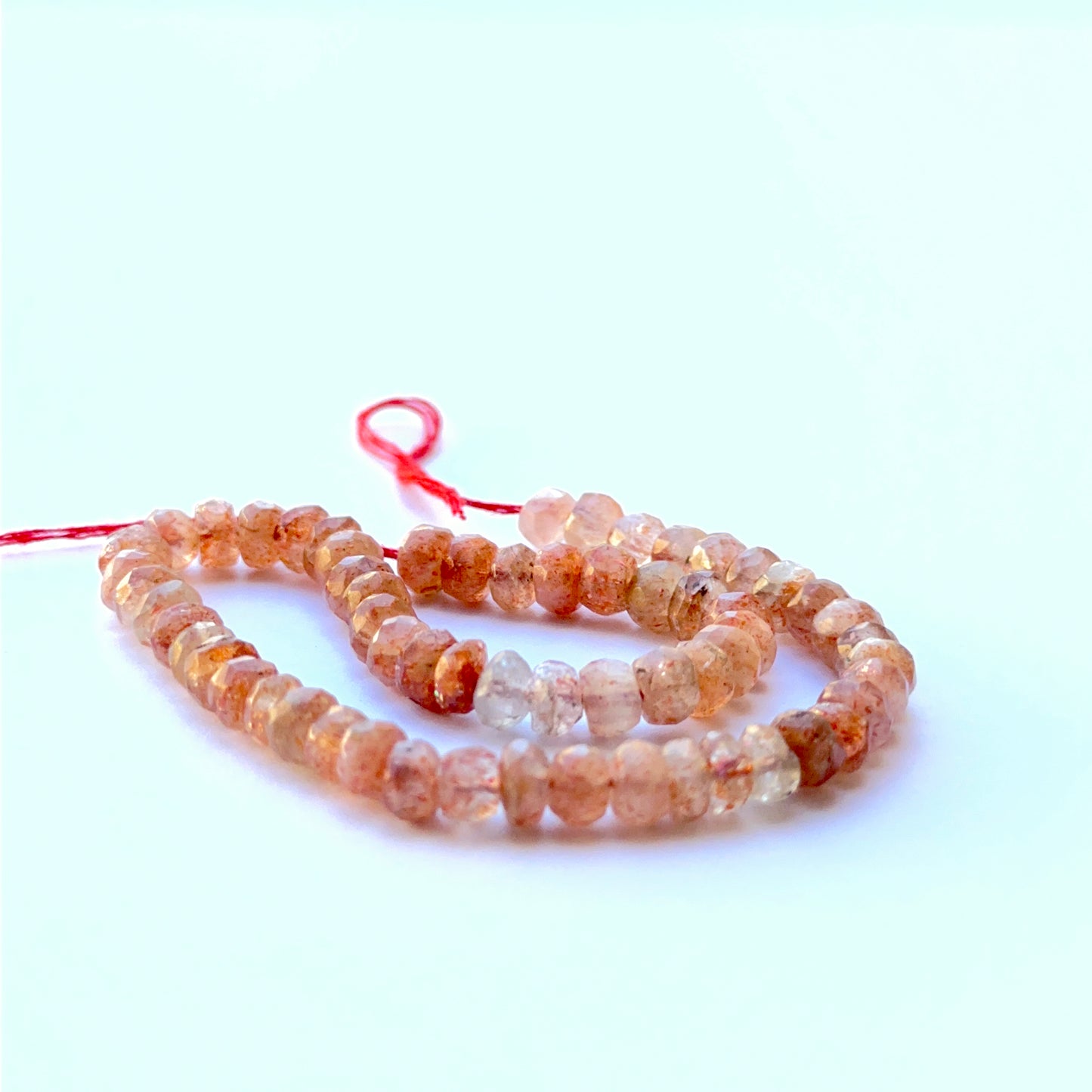 Sunstone faceted rondelle beads aligned on a strand highlighting clarity, shine and consistent 5mm sizing.