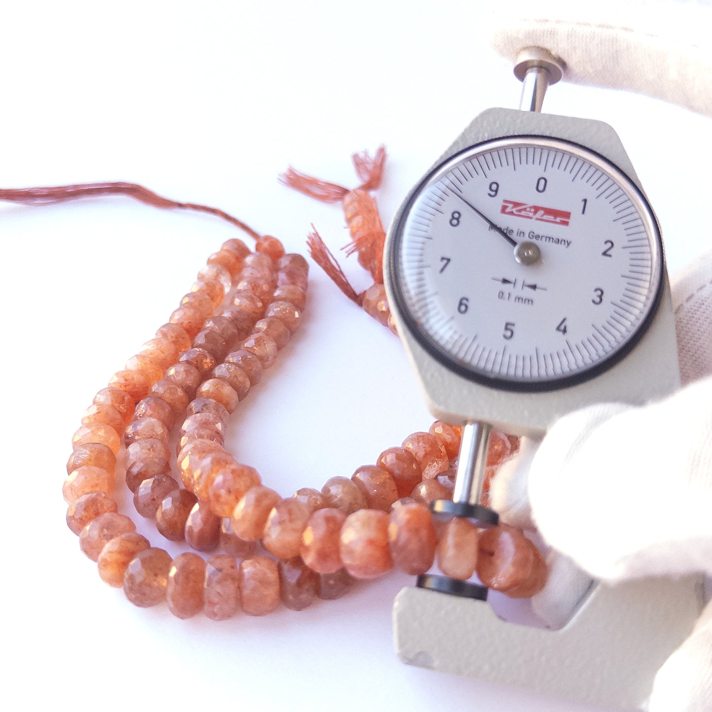 A dial gauge measures the Sunstone faceted rondelle 7–9.5mm gemstone.