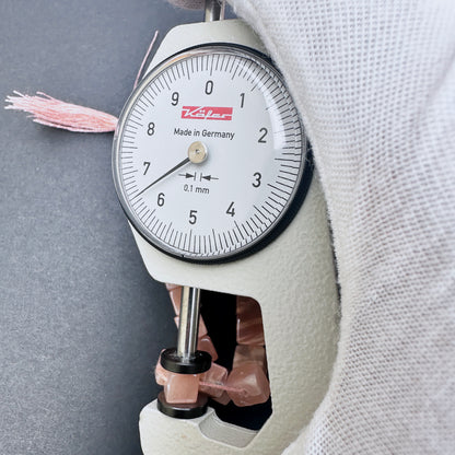 A dial gauge measures the Sunstone smooth square 5.5-6mm gemstone.