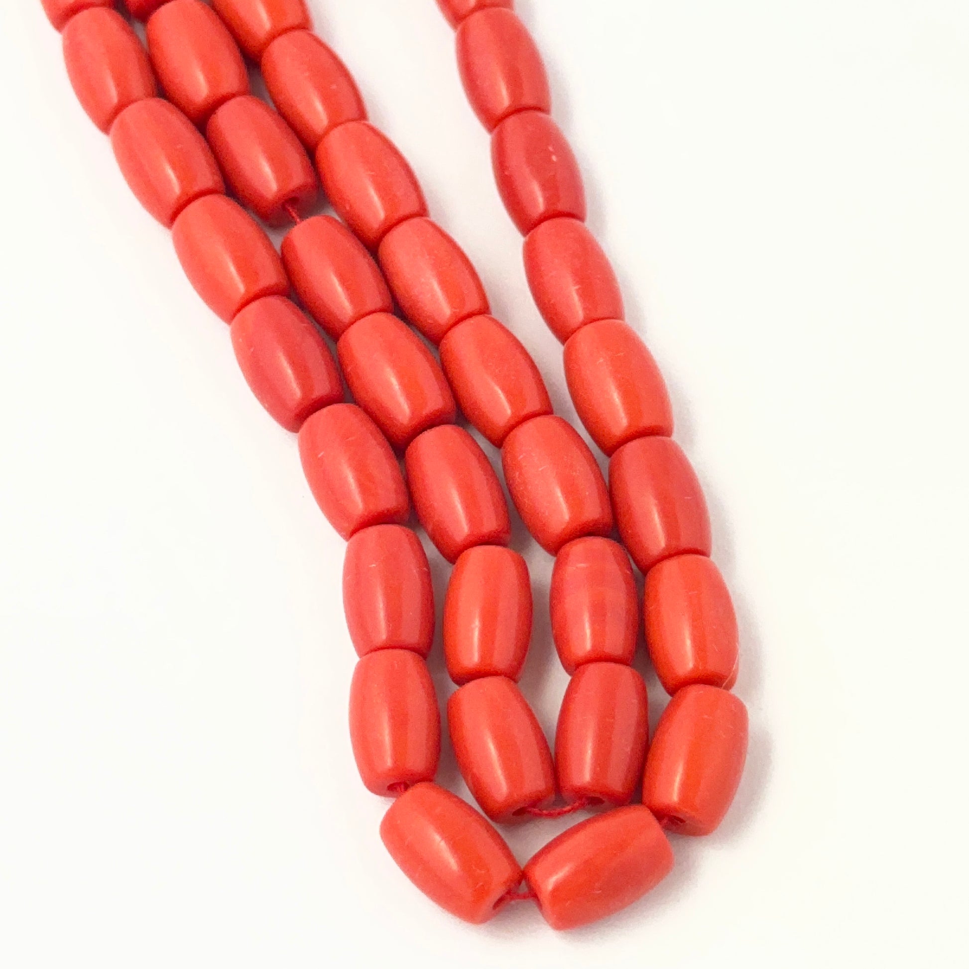 Drum shaped Taiwan Coral stone beads displayed in a strand to highlight their warm tone and consistent bead quality.
