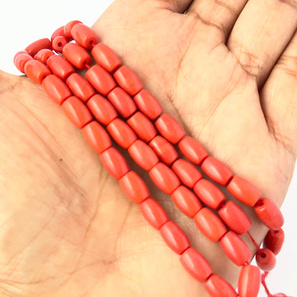A person holds delicate strands of Taiwan Coral beads, showcasing their smooth design for jewellery making.