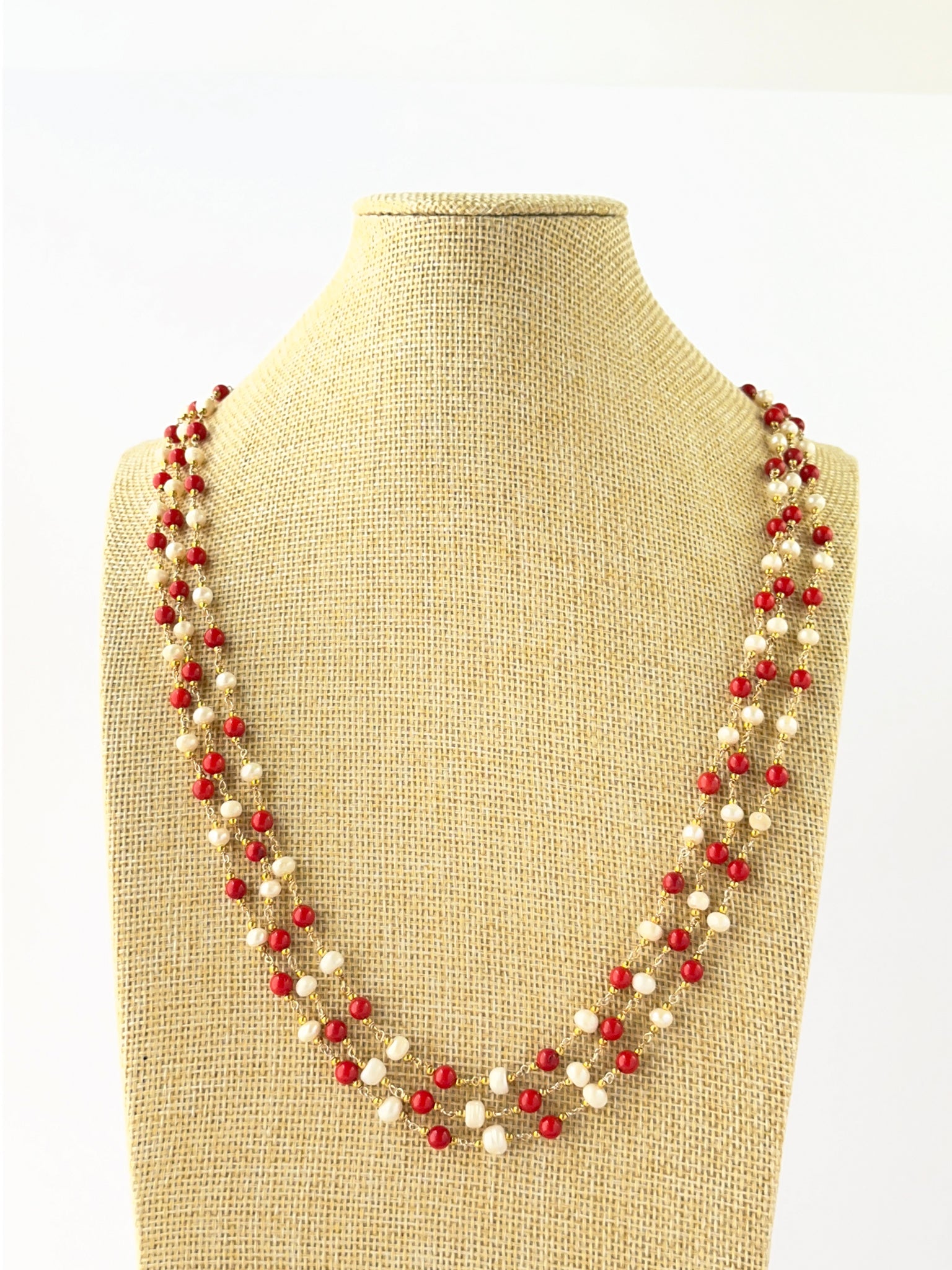 Three-strand necklace combining smooth round Taiwan coral and freshwater pearl 5mm beads in layered lengths.