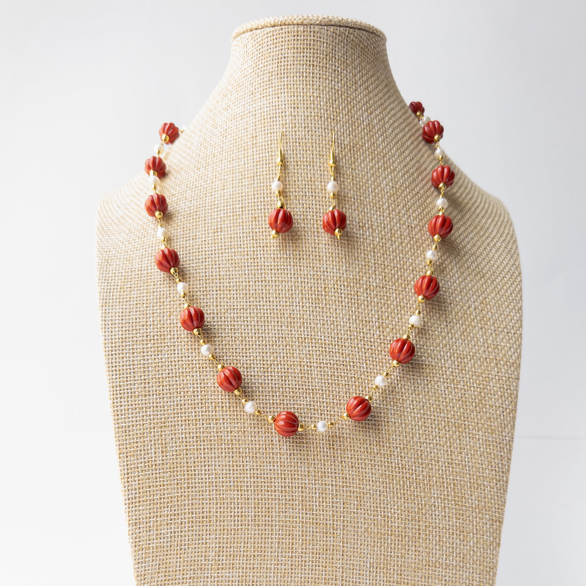 Authentic Taiwan Coral jewellery showcasing detailed curved pumpkin carving and a coordinated necklace and earring design.