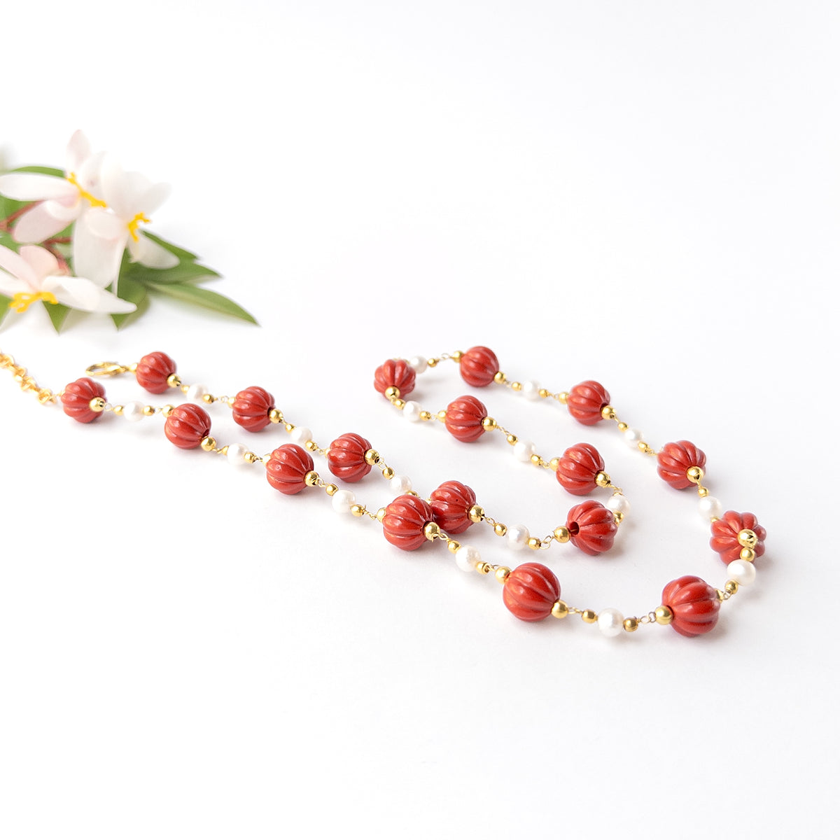 Handmade jewellery featuring carved Taiwan Coral beads complemented by luminous pearl accents and gold-tone findings.