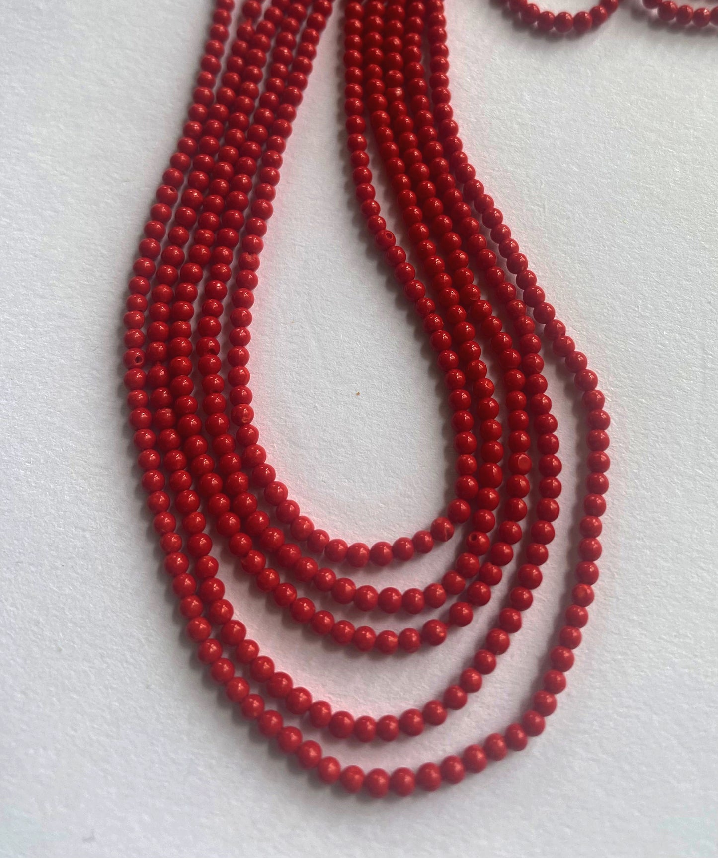 Smooth round coral gemstones in rich red tones strung evenly across a 34cm strand.