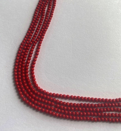 Bright red Taiwan Coral beads neatly arranged in a 34cm strand with smooth round cuts and glossy polish.
