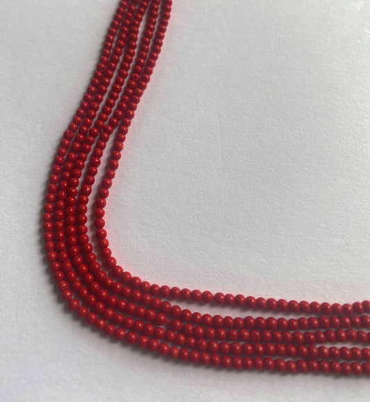 Bright red Taiwan Coral beads neatly arranged in a 34cm strand with smooth round cuts and glossy polish.