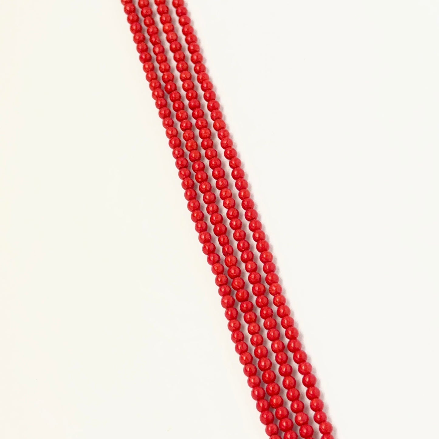 Taiwan Coral smooth round beads displayed on a strand to highlight their delicate size and coral tone.