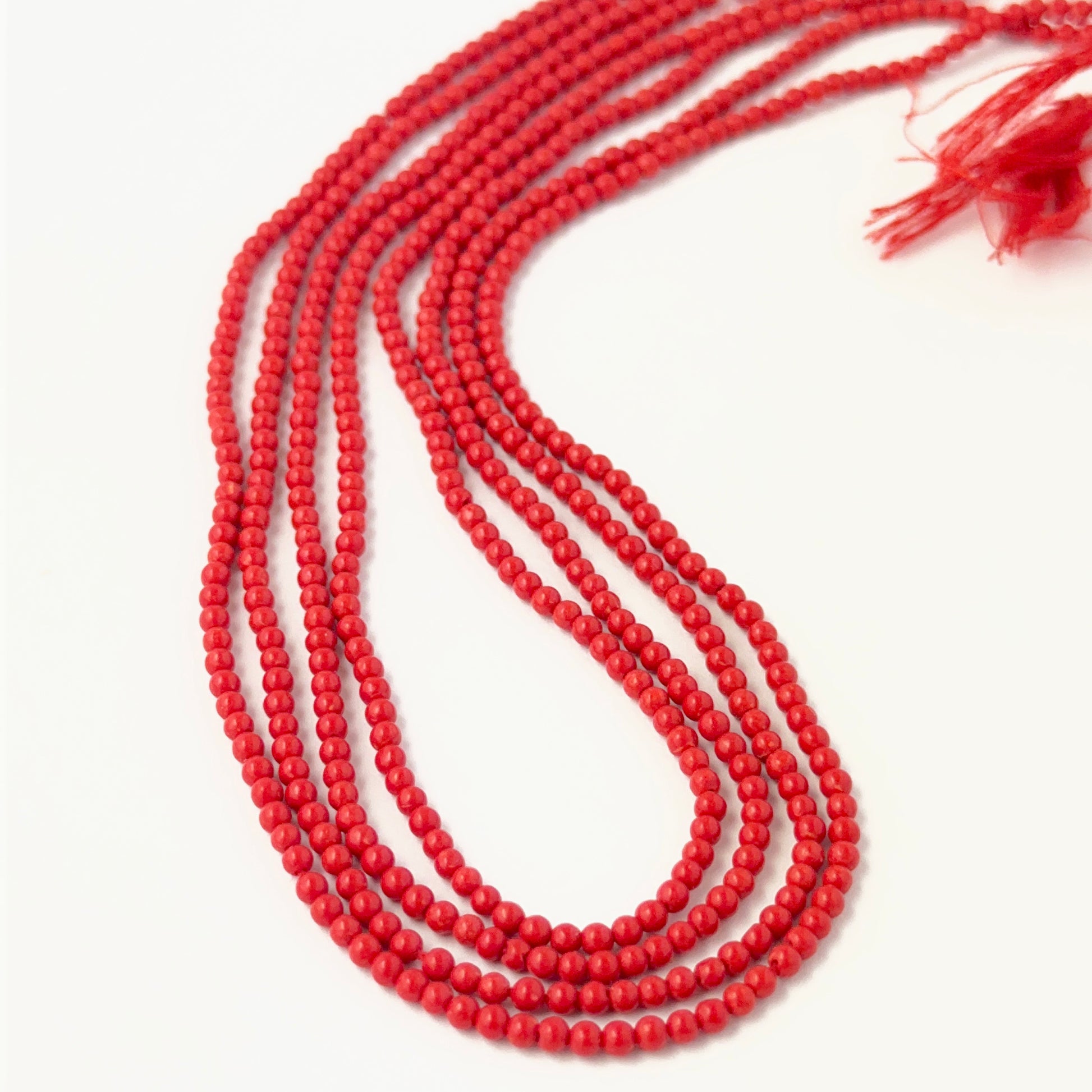 Close‑up of Taiwan Coral round beads showing detailed surface texture and vibrant coral colour.