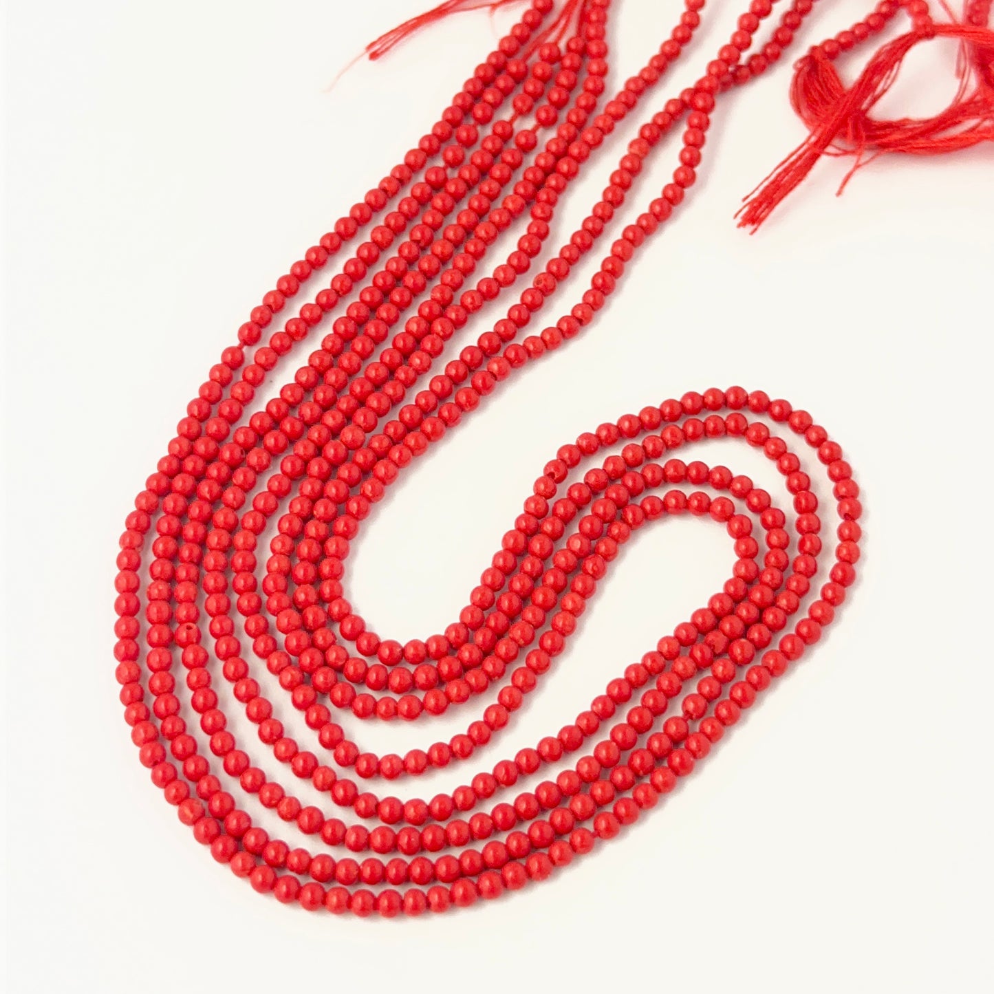 Taiwan Coral smooth round 2.3mm beads arranged neatly on a 34cm strand for DIY jewellery making.