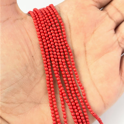 A person holds delicate strands of Taiwan Coral beads, showcasing their smooth design.