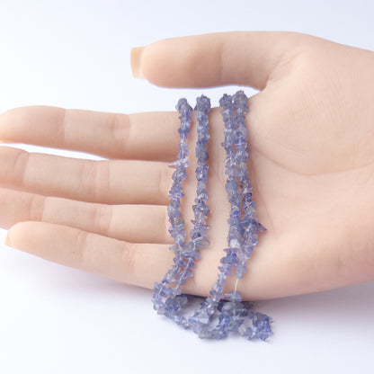 A person holds delicate strands of Tanzanite beads, showcasing their chip design.