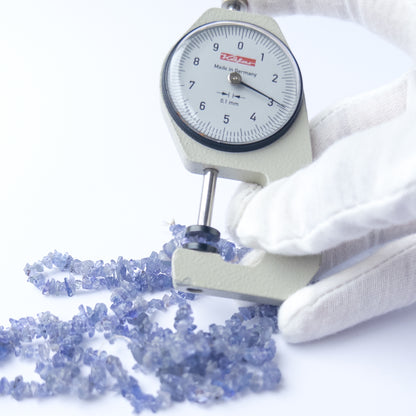 A dial gauge measures the Tanzanite chip 3–4mm gemstone.