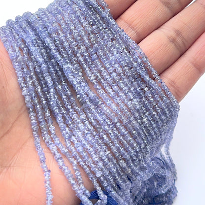 A person holds delicate strands of tanzanite beads, showcasing their faceted design.