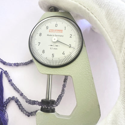 A dial gauge measures the Tanzanite faceted rondelle 3.1mm gemstone.