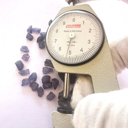 A dial gauge measures the Tanzanite rough cut 5-6mm gemstone.