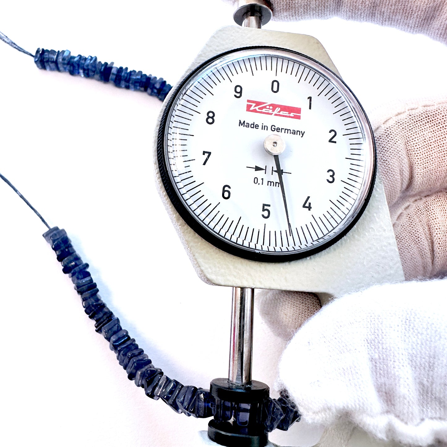 A dial gauge measures the Tanzanite square heishi 4.5mm gemstone.