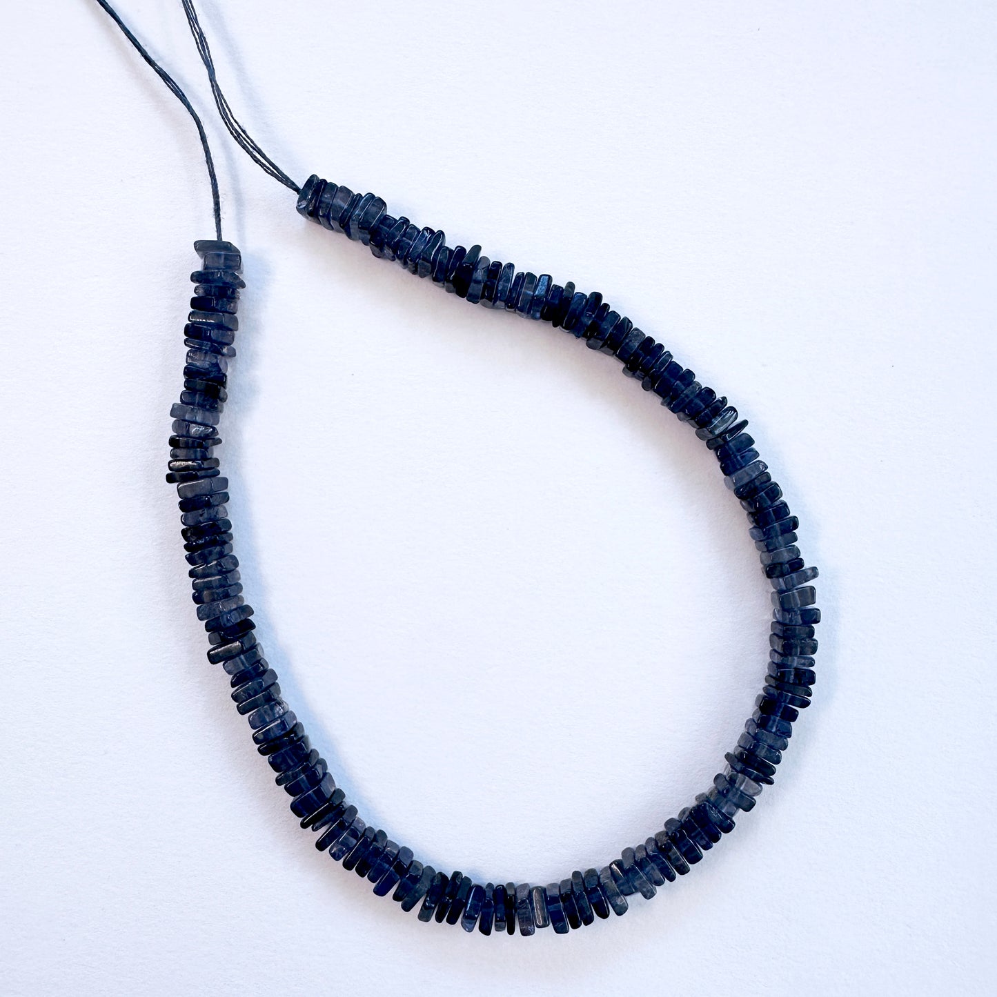 Natural gemstone beads in Tanzanite, arranged neatly on a strand for DIY jewellery.