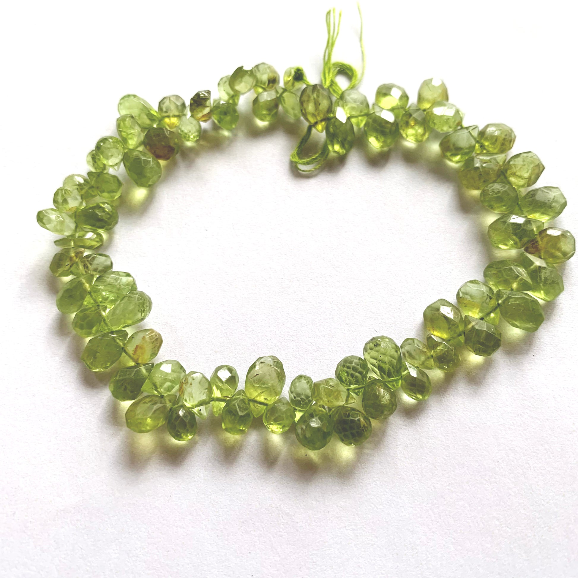 A dial gauge measures the Peridot pear-shaped briolette 4–5.5mm gemstone.