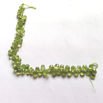 Close-up showcasing the pear-shaped Peridot briolette cut and luminous green hue.