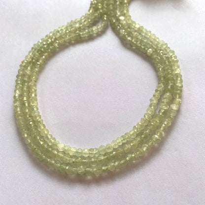 Prehnite gemstone beads strung in a continuous loop, reflecting light from their faceted surfaces.