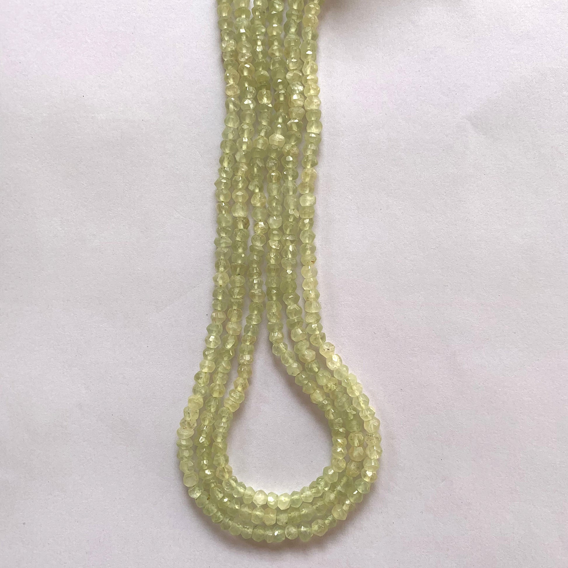 Macro shot of Prehnite beads highlighting their clarity, symmetry, and subtle green glow.