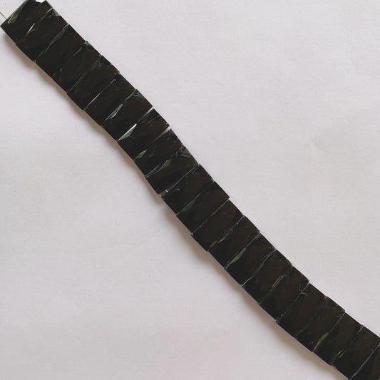 Close-up of glossy Black Onyx faceted rectangle beads highlighting their 9.0–9.5mm breadth and sharp cuts.