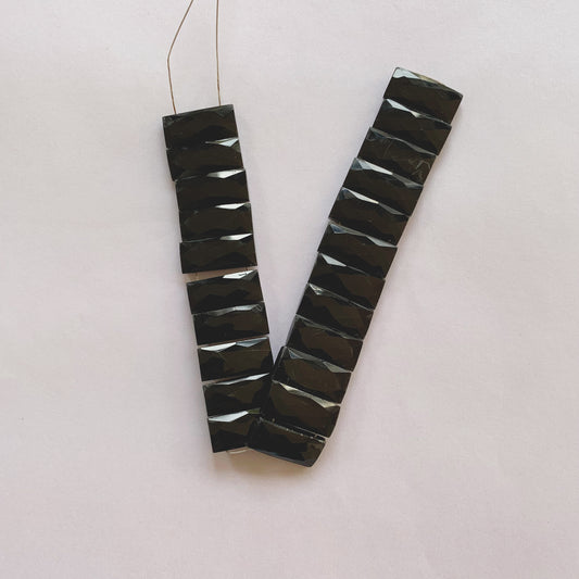 Jet-black faceted rectangle onyx beads in 20mm by 9mm size strung on a 20cm strand for jewellery making.