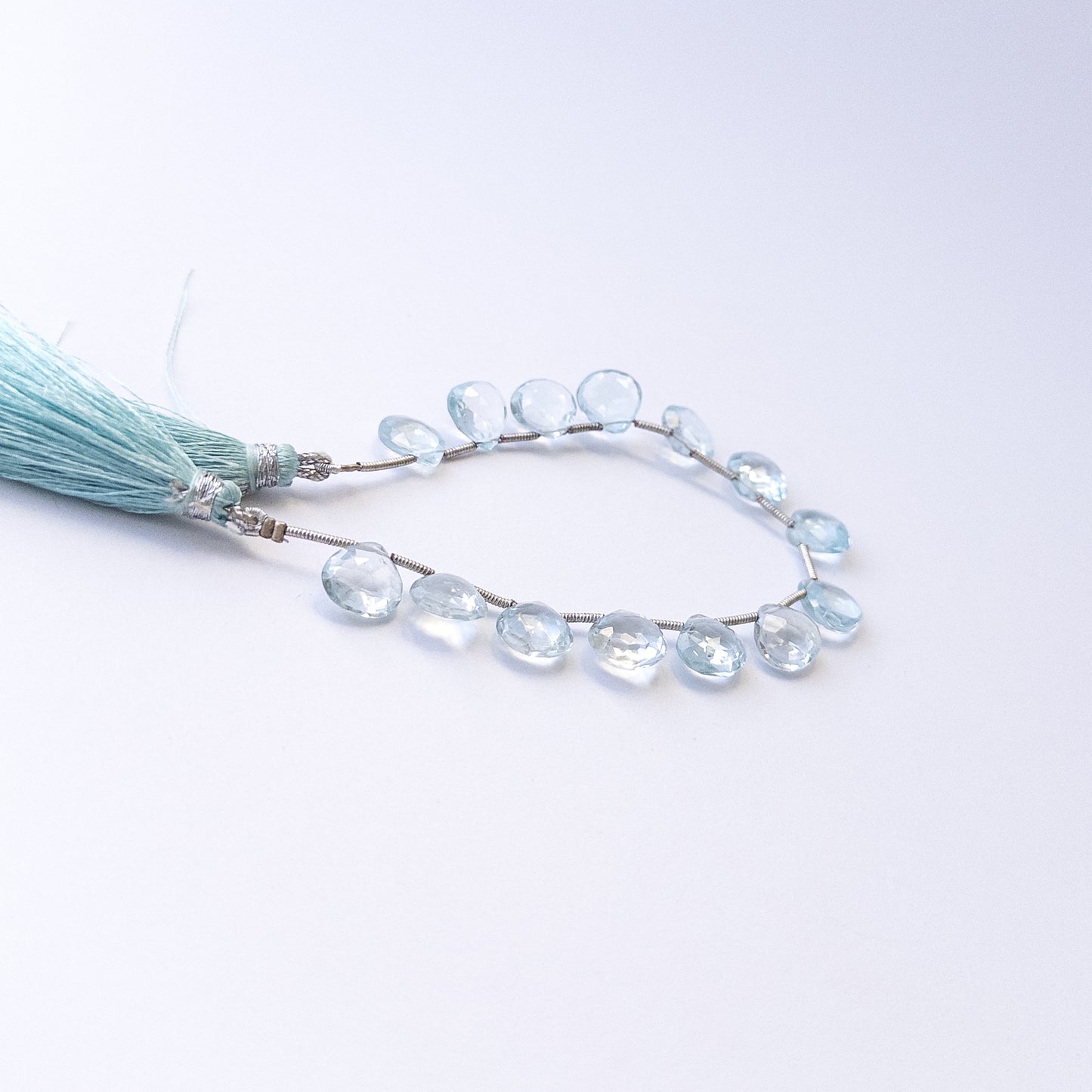 Genuine Topaz gemstone beads showcasing faceted briolette cuts arranged neatly in 14‑piece sets.