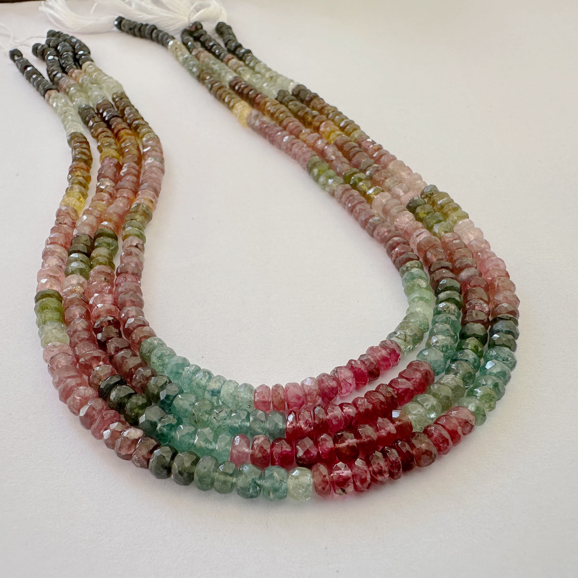 Natural Tourmaline rondelles arranged on thread with glossy finish and neat alignment.