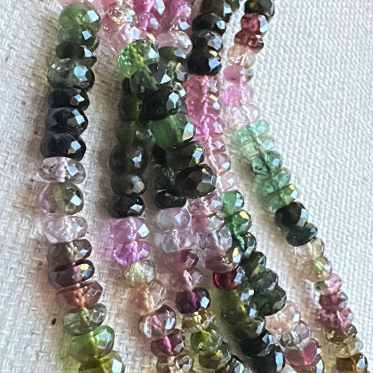 Mixed tourmaline rondelle beads in soft pinks, greens, and golds laid out uniformly across the strand.
