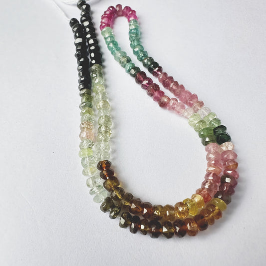 Close-up of multi-coloured Tourmaline stone beads, faceted rondelle cut, sparkling under light.