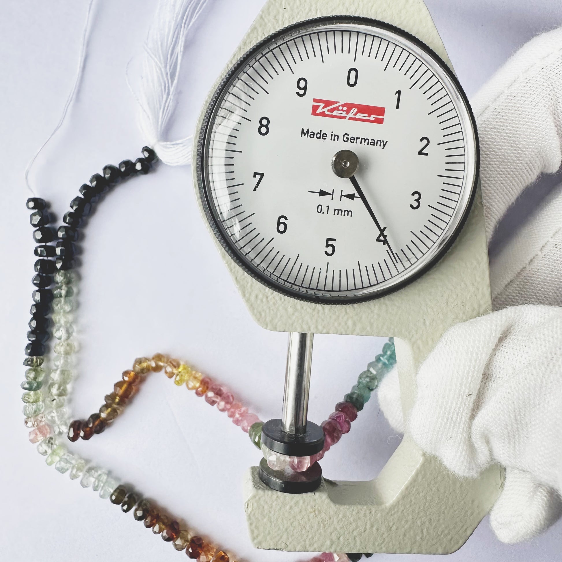 A dial gauge measures the Tourmaline faceted rondelle 4mm gemstone.