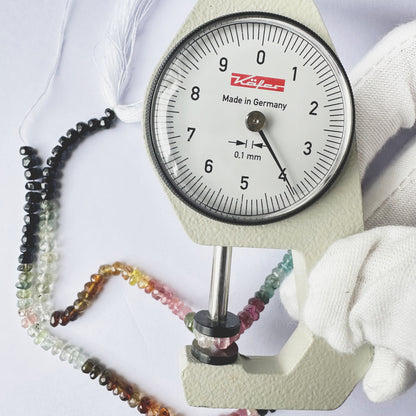 A dial gauge measures the Tourmaline faceted rondelle 4mm gemstone.