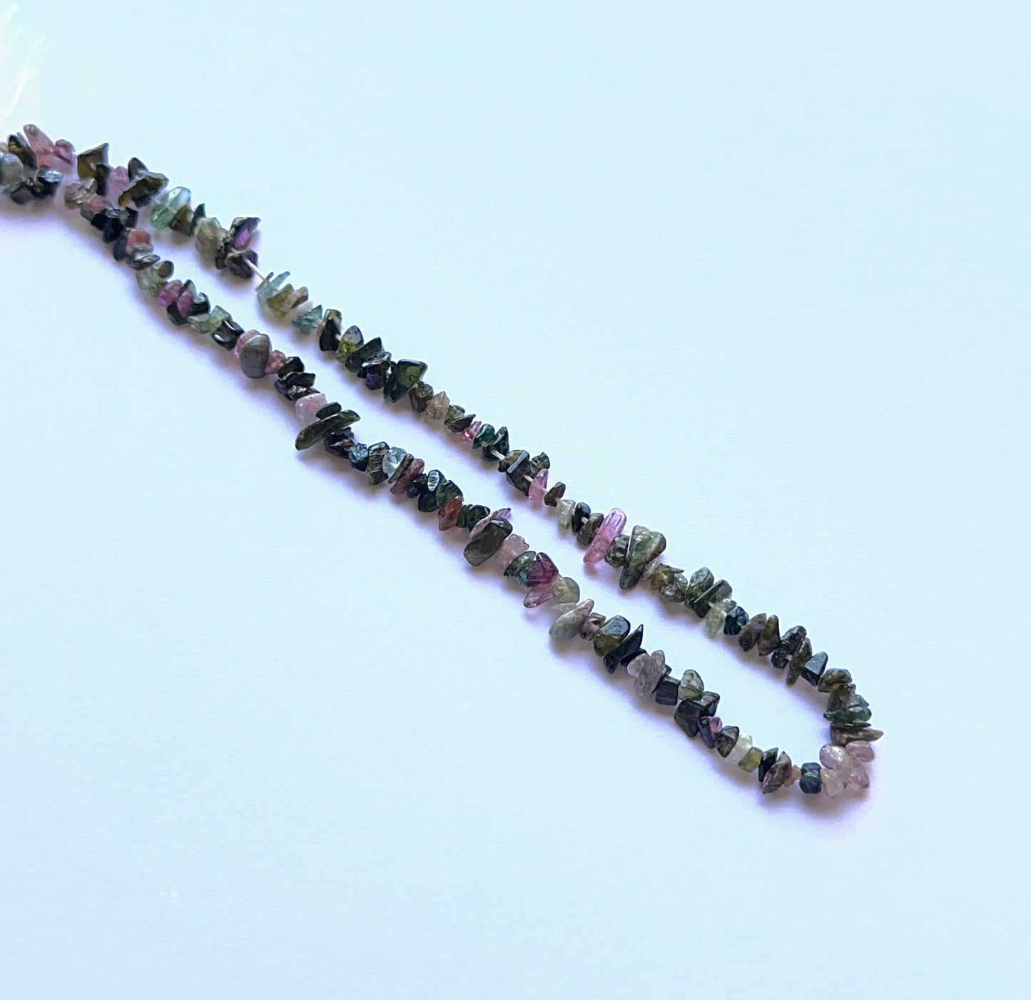 Tourmaline rough chips aligned on a strand highlighting colour variety, natural inclusions and rustic charm.