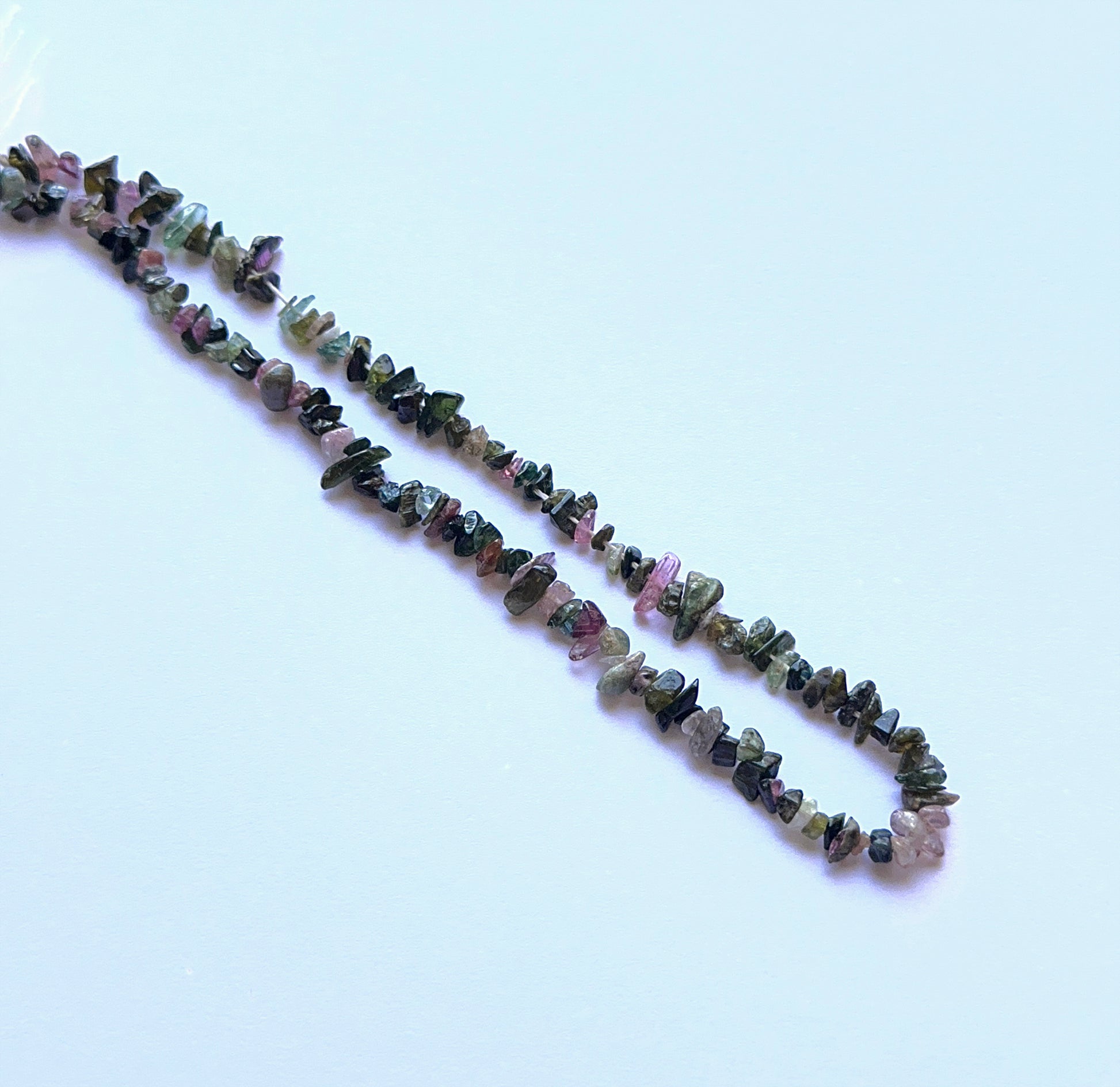 Tourmaline rough chips aligned on a strand highlighting colour variety, natural inclusions and rustic charm.
