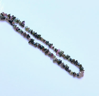Tourmaline rough chips aligned on a strand highlighting colour variety, natural inclusions and rustic charm.
