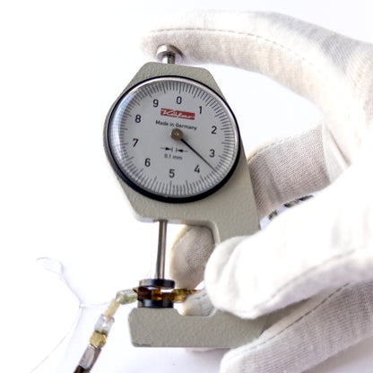 A dial gauge measures the Tourmaline smooth rectangle 3–3.6mm gemstone.