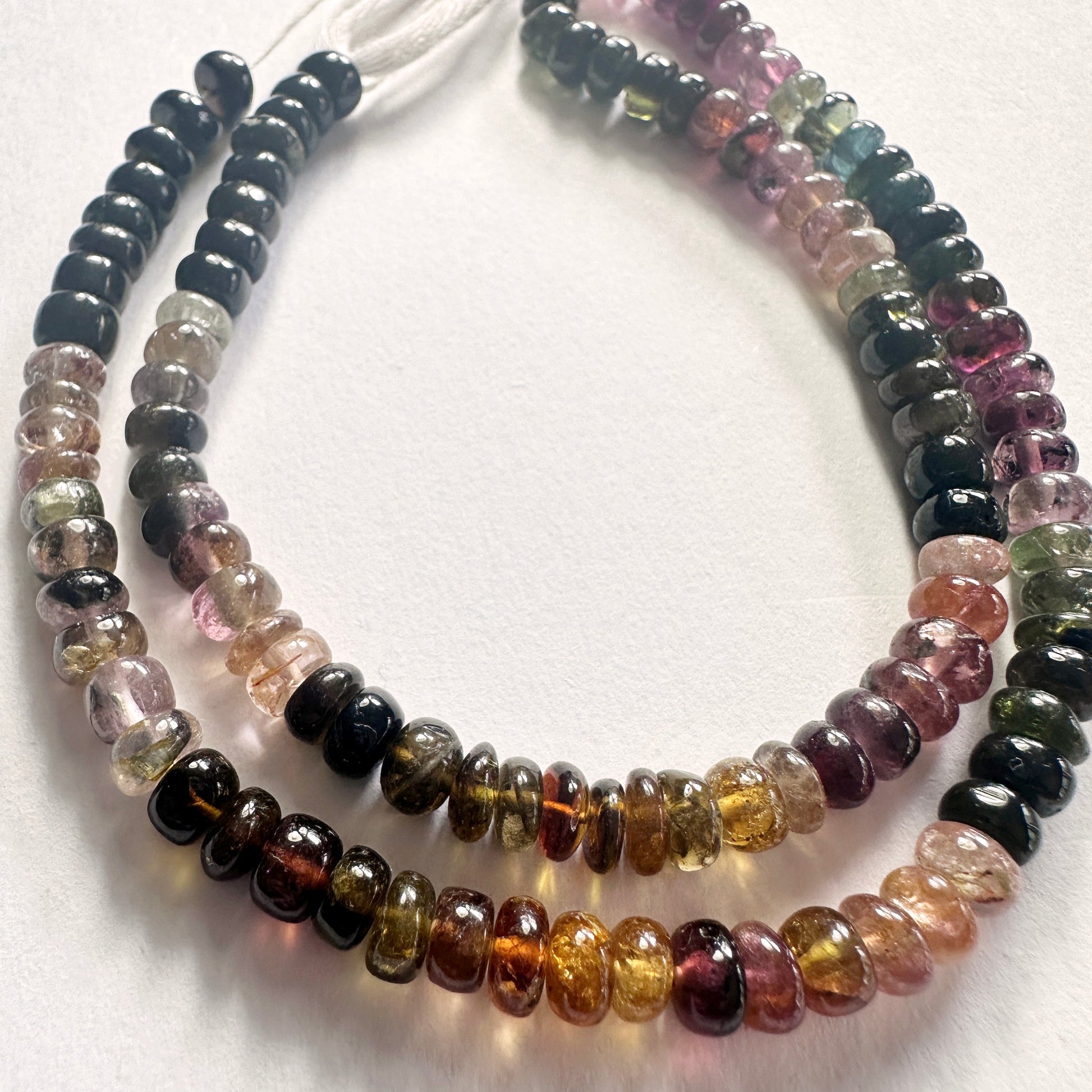 Strand of tourmaline beads with consistent sizing and glossy finish across a 37cm length.