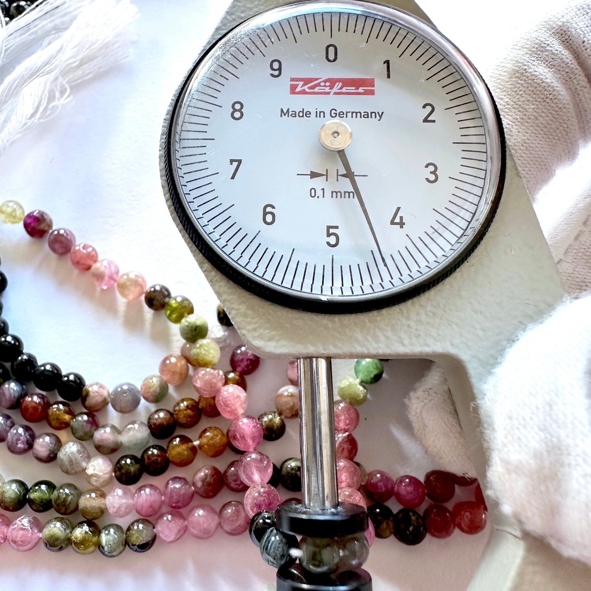 A dial gauge measures the Tourmaline smooth round 4.3-4.7mm gemstone.
